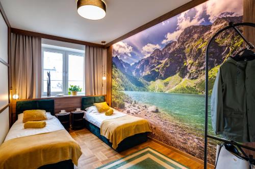 two beds in a room with a painting on the wall at Apartamenty Centrum 50 m od Rynku, FREE PARKING in Nowy Targ