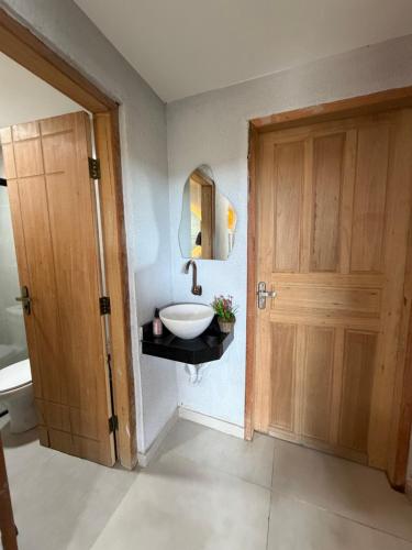 a bathroom with a sink and a wooden door at Chalé Dona Ceci in Cavalcante