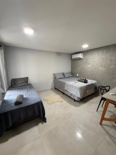 a bedroom with two beds and a table in it at Chalé Dona Ceci in Cavalcante