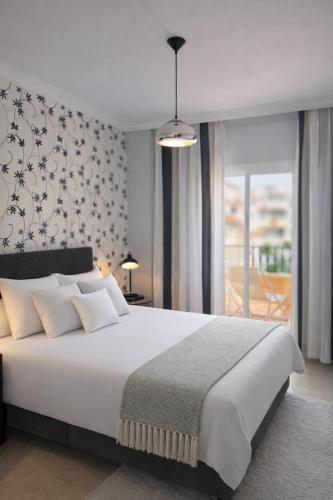 a bedroom with a large white bed and a balcony at Apartamentos Abril in Nerja