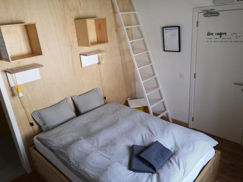a bedroom with a bed with a ladder on the wall at Hostel do Mar in Carrapateira