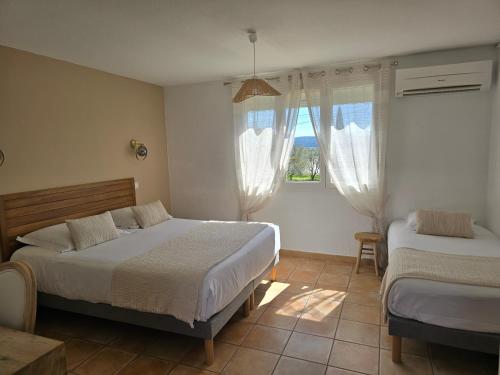 a bedroom with two beds and a window at Le Mas des Quintrands Manosque - Motel de charme in Manosque