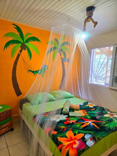 a bedroom with a bed with a painting of a palm tree at L'Orange Volcanique in Saint-Pierre