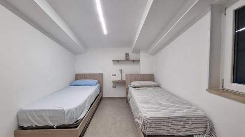 two beds in a small room with a window at Cilento My Home in Albanella