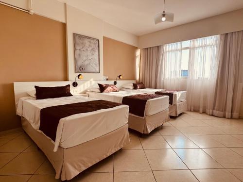 a hotel room with three beds and a window at Hotel Binder Quality Inn in Mogi das Cruzes