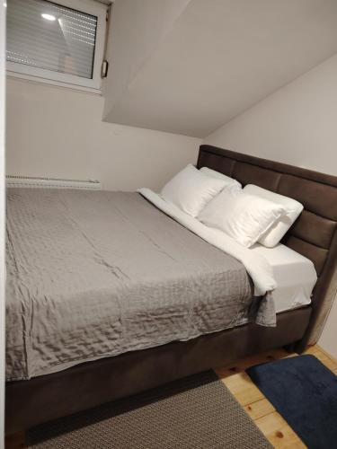a bed with white pillows and a window in a room at Vikend kuća na Dunavu - Vila Čoče in Kovin