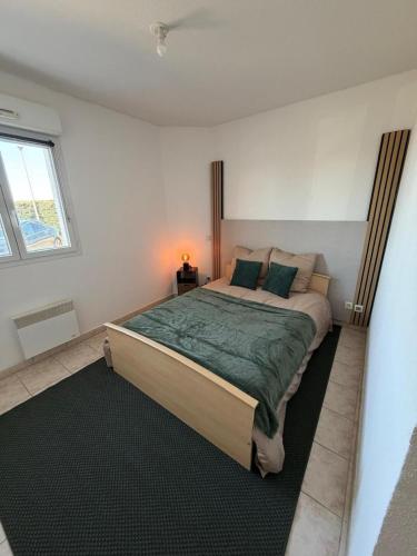 a bedroom with a large bed with a green blanket at La Pause Larzac- T3 calme-terrasse - Proche Viaduc de Millau in La Cavalerie