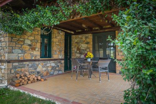 a patio with a table and chairs and a stone wall at Platanorema in Agios Ioannis Prodromos