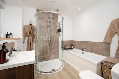 a bathroom with a shower and a tub and a sink at Shore View Cottage in Inverness
