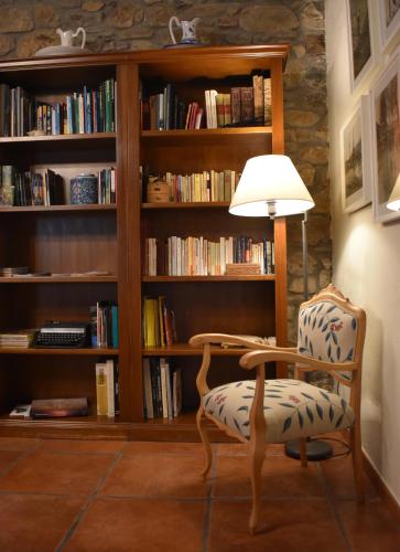a chair and a lamp in front of a book shelf at Hotel Rural CHOUSA VERDE in Vegacervera