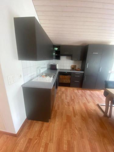 a kitchen with black cabinets and a wooden floor at Wachtgasse in Adliswil