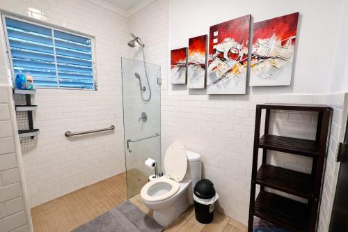 a bathroom with a toilet and three paintings on the wall at Emmanuelli Sur 7 Bedroom Mall of San Juan Home in San Juan