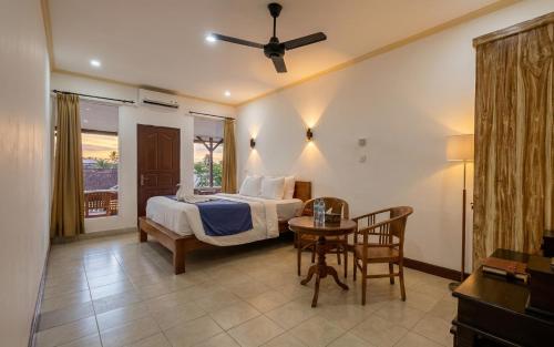 a bedroom with a bed and a table in a room at Rumah Rini by Rumah Weda in Ubud