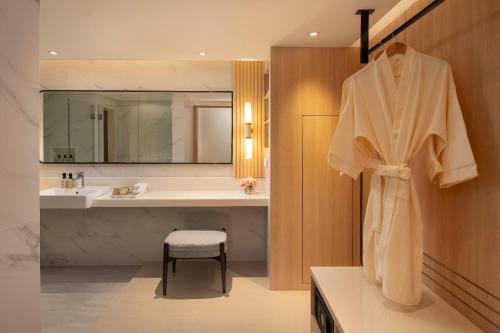 a bathroom with a sink and a robe hanging on a wall at Amari Don Muang Airport Bangkok in Bangkok