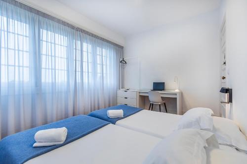 a bedroom with two beds and a desk and a window at HI Coimbra - Pousada de Juventude in Coimbra