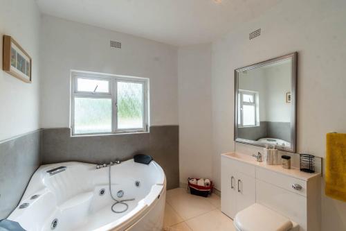 a white bathroom with a tub and a mirror at Borrowdale Top End - Apartments in Harare