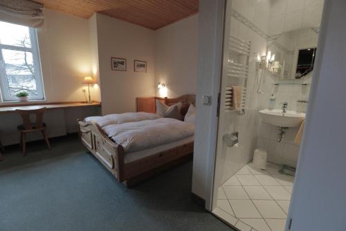 a bedroom with a bed and a bathroom with a sink at Vergissmeinnicht in Oberhof