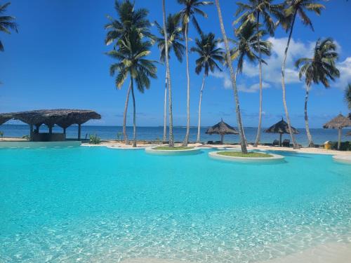 a pool on the beach with palm trees and the ocean at Antonio Beach in Uroa