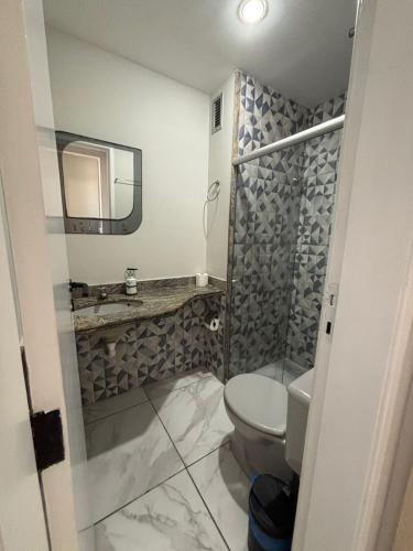 a bathroom with a toilet and a sink and a mirror at Flat Jardim de Allah in Campos dos Goytacazes