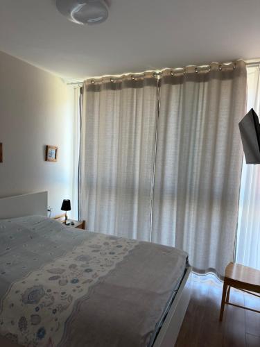 a bedroom with a bed and a window with curtains at Sea view apartments in Caesarea