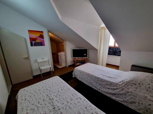 a attic room with two beds and a television at Breve Sosta in Santhià