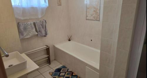 a white bathroom with a tub and a sink at Ocean Whisper 405 in Scottburgh