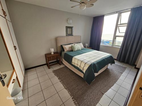 a bedroom with a bed and a large window at Ocean Whisper 405 in Scottburgh