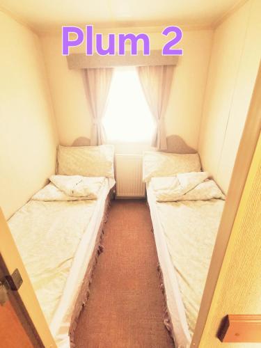 two beds in a room with a window at Plum 2, luxury 3 bed 8 berth, gas central heating, bedding included, Static caravan with large wrap around secure veranda on Coral Beach in Ingoldmells in Ingoldmells