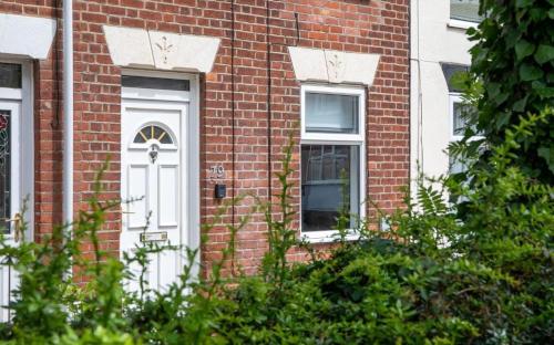 a brick building with a white door and windows at Bright 3 bedroom townhouse near city centre in Norwich