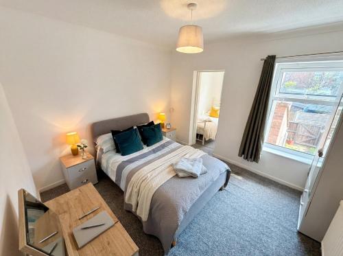 a bedroom with a bed and a table and a window at Bright 3 bedroom townhouse near city centre in Norwich