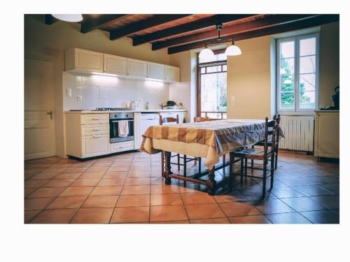 een keuken met een tafel en een keuken met witte apparaten bij maison bourgeoise in Rouffignac
