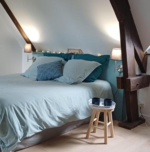 a bedroom with a large bed with a wooden stool at Retour en Baie in Pendé