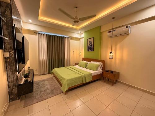 a bedroom with a bed with green walls and a television at Dreamland royal suite in Rawalpindi