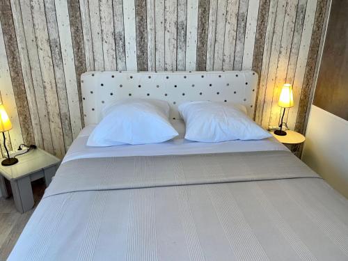 a white bed with two white pillows and two lamps at Le Relais du 49 - Gîte in La Séguinière