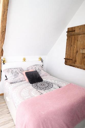 a bedroom with a bed with a pink blanket at La Manch'hôtes in Domjean