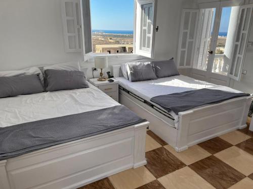 two beds in a room with two windows at Duplex Villa 4 rooms in Marsa Matruh