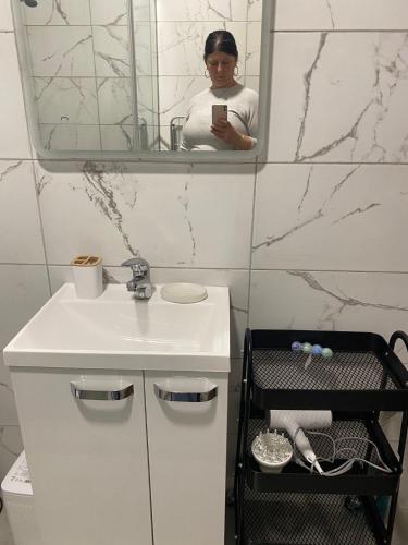 a woman taking a picture of a bathroom with a sink at Apartman Park in Stara Pazova