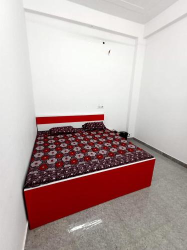a bedroom with a red bed in a white room at Hotel Swami in Gogameri