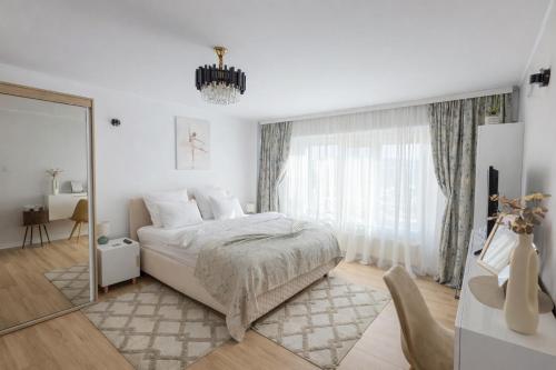 a white bedroom with a bed and a mirror at Central Modern View- unitate autorizată de Ministerul Turismului in Râmnicu Vâlcea
