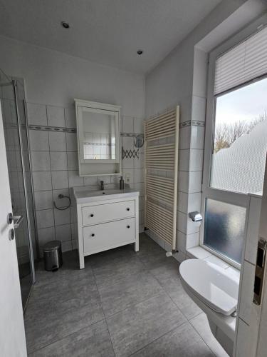 a bathroom with a sink and a toilet and a window at Apartment am Steinweg in Emden