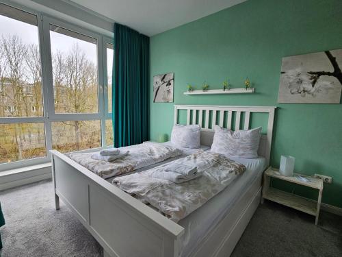 a bedroom with a bed with green walls and a window at Apartment am Steinweg in Emden