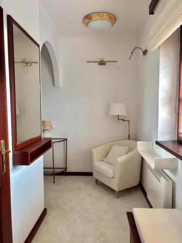 a white living room with a chair and a mirror at Apartmán Ela in Komárno