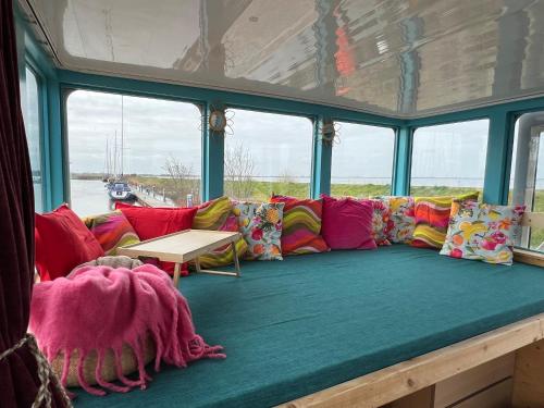 a couch with colorful pillows in a room with windows at WoonBoten Anna in Andijk