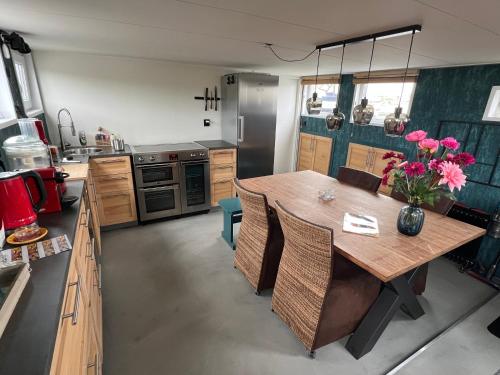 a kitchen with a wooden table with pink flowers on it at WoonBoten Anna in Andijk