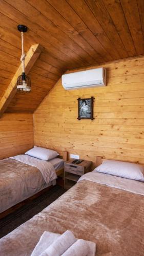 a room with two beds in a wooden cabin at Etno Lug - Village in Bogetići