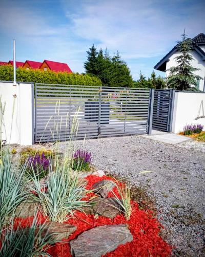 a garden with red flowers and a fence at Mistral Jarosławiec in Jarosławiec
