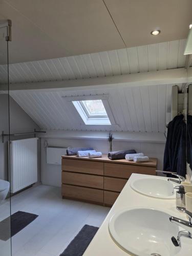 a attic bathroom with a sink and a window at StayTommy in Bertem