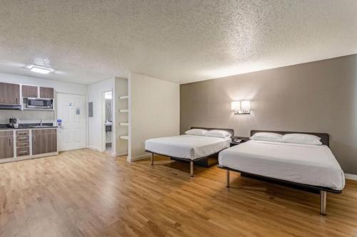 two beds in a large room with wooden floors and a kitchen at Everstay Living in Dallas
