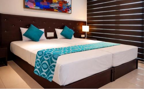 a bedroom with a large bed with blue pillows at TBRS By Platinum Hotels in Trincomalee