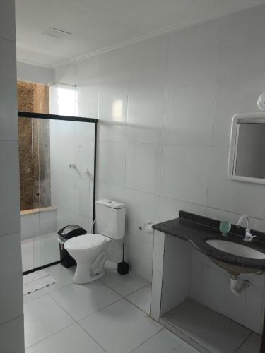 a white bathroom with a toilet and a sink at Paraíso do Abais, house for rent in Estância